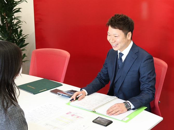 物件資料を開き、お客様と向かい合って話すスタッフ